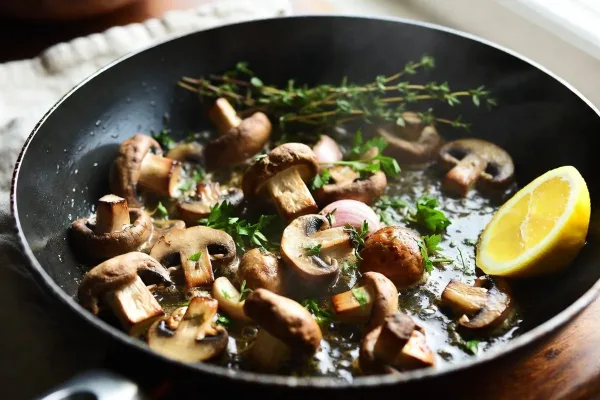 Golden-brown cremini mushrooms with garlic, thyme, and lemon in a skillet