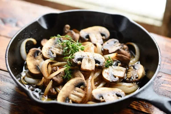 Sautéed cremini mushrooms and golden onions with thyme in a cast-iron skillet