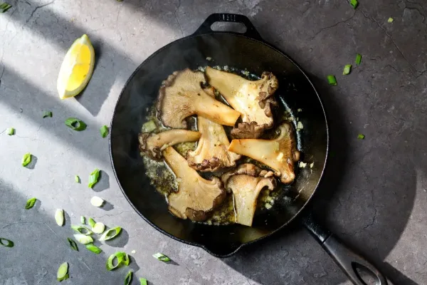 Crisp-edged oyster mushrooms with garlic butter and lemon in a skillet